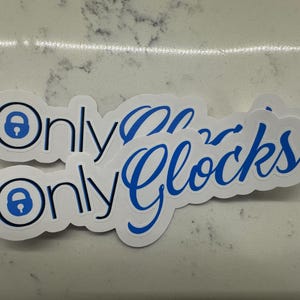 May include: Two white stickers with blue text and a blue padlock icon. The text on the stickers reads "Only Glocks".