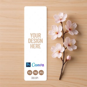 Może przedstawiać: Biała zakładka z napisem "YOUR DESIGN HERE" oraz logo Canva i Photoshop. Gałązka różowych kwiatów wiśni spoczywa na jasnej drewnianej powierzchni.
