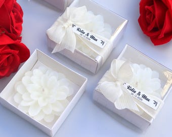 Peut inclure: Bougies blanches en forme de fleur dans des boîtes transparentes avec des nœuds blancs et des étiquettes indiquant "Kelia & Max 08.12.2020". Des roses rouges sont placées autour des boîtes. Cadeau de mariage ou d'événement.