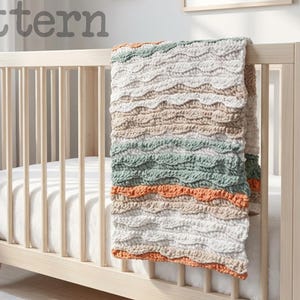 Pode incluir: Uma manta de crochê com textura ondulada sobre um berço de madeira clara. A manta apresenta listras horizontais em branco, bege, verde sálvia e laranja queimado. A palavra pattern está impressa em cinza no canto superior esquerdo.