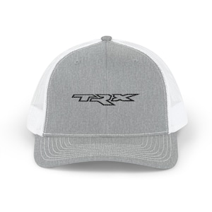 May include: A gray trucker hat with a white mesh back and a curved brim. The front of the hat features the black letters "TRX" in a stylized font. The hat has a snap closure.