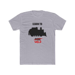 May include: A heather gray t-shirt with the text "LEARN TO CODE" above a black silhouette of a bulldozer, with "CODE" crossed out and "WELD" in red below. The shirt is a casual wear item.