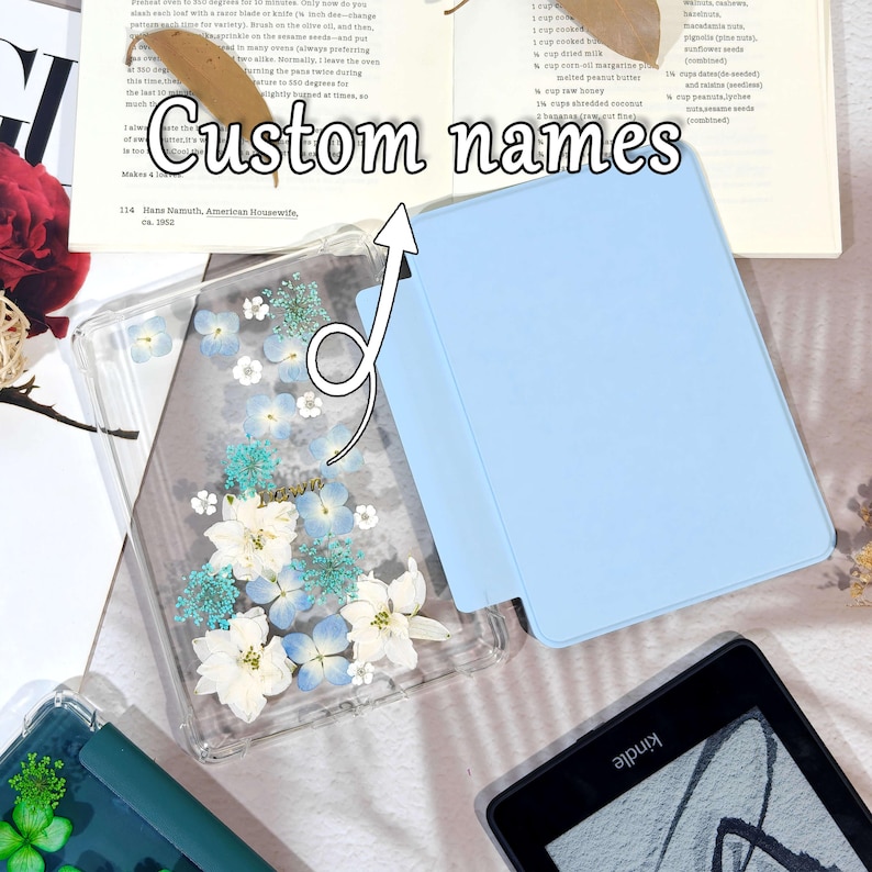 K&ouml;nnte beinhalten: Eine transparente Handyh&uuml;lle mit gepressten wei&szlig;en und blauen Blumen und dem Wort "Love". Daneben befindet sich eine hellblaue Tableth&uuml;lle. Der Text "Custom names" ist im Bild. Ein Kindle-E-Reader ist ebenfalls sichtbar.