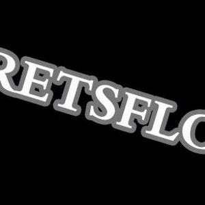 May include: The text "@FLORETSFLOWERS" is displayed in white, with a gray outline, set against a black background. The text is angled diagonally across the image, with the "@" symbol preceding the brand name.