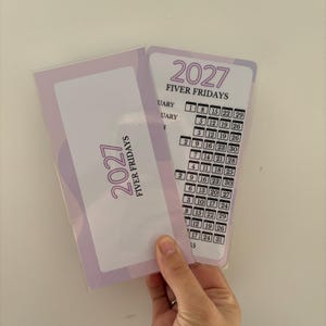 May include: Two rectangular laminated cards featuring a light purple and white colour scheme. The text reads 2027 FIVER FRIDAYS. One card displays a grid of dates organised by month, while the other card shows the title and year in a vertical orientation.