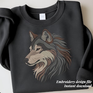 May include: A dark grey sweatshirt with an embroidered wolf head design in shades of brown, grey, and beige. The text "Embroidery design file Instant download" is printed at the bottom. The sweatshirt has a crew neck and long sleeves.