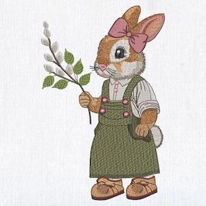 May include: A brown bunny wearing a green overall dress with a pink bow in its hair. The bunny is holding a branch with green leaves and white buds.