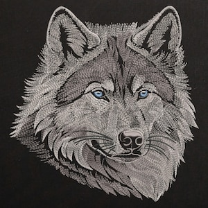 Puede incluir: Primer plano de la cara de un lobo gris con ojos azules. El lobo está bordado sobre un fondo negro.