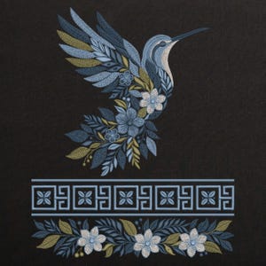 Puede incluir: Diseño bordado de un colibrí en vuelo, con detalles florales y de hojas azules, blancas y doradas. El ave se encuentra sobre un fondo negro, con un borde floral a juego en la parte inferior.