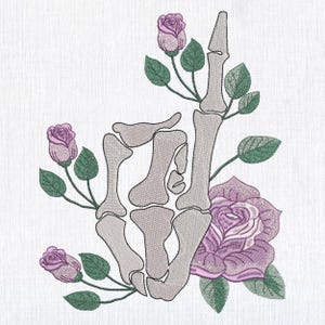 Puede incluir: Diseño bordado de una mano esquelética con el dedo medio levantado, rodeada de rosas moradas y hojas verdes. El diseño está sobre un fondo blanco, creando un contraste entre los colores oscuros y claros.