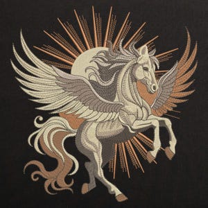 Könnte beinhalten: Gestickte Darstellung eines weißen geflügelten Pferdes mit brauner Mähne und Schweif, das vor einem Sonnenstrahl mit goldenen Strahlen steht.