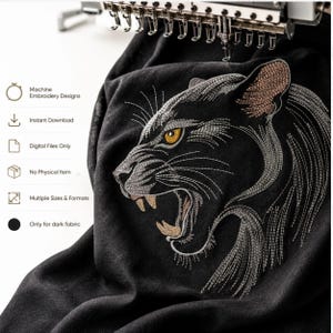 May include: A black fabric featuring a detailed machine embroidery design of a snarling panther head with golden eyes and sharp teeth. The embroidery uses silver, grey, and gold thread. Text includes Machine Embroidery Designs, Instant Download, Digital Files Only, No Physical Item, Multiple Sizes & Formats, and Only for dark fabric.
