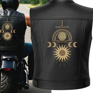 May include: Black leather vest with a celestial design on the back. The design features a sun, crescent moons, and other geometric shapes in a gold colour. The vest has a classic biker style with a button closure.