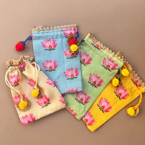May include: Four small drawstring bags with floral patterns. The bags are made of fabric and have a light blue, green, yellow, and cream color. Each bag has a tassel.
