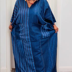 May include: A long, blue and white striped dress with a V-neck and two pockets. The dress is made of a lightweight fabric and has a relaxed fit.