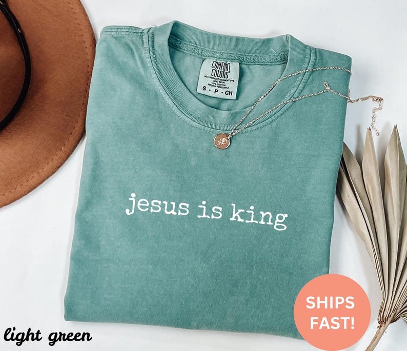 K&ouml;nnte beinhalten: Hellgr&uuml;nes T-Shirt mit dem Text "jesus is king" in wei&szlig;en Buchstaben.