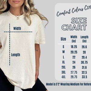 May include: A cream-colored t-shirt with a size chart and the text "Comfort Colors C1717." The size chart shows measurements in inches for width and length, ranging from size small to 4XL. The model is 5'2" and wearing a medium.