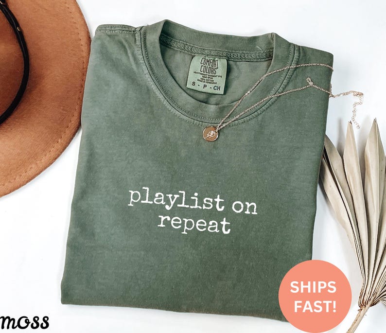 May include: Green t-shirt with the text "playlist on repeat" in white lettering.
