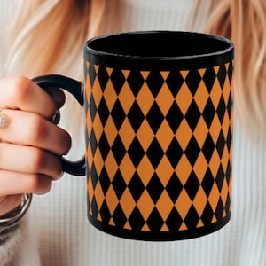 May include: A black coffee mug with a diamond pattern in orange and black.