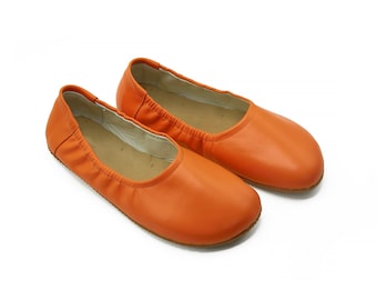 May include: A pair of orange leather ballet flats. The flats have a simple design and are made of a soft, supple leather.
