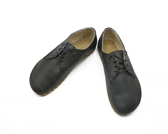 May include: A pair of black leather lace-up shoes with a rounded toe and a flat sole.