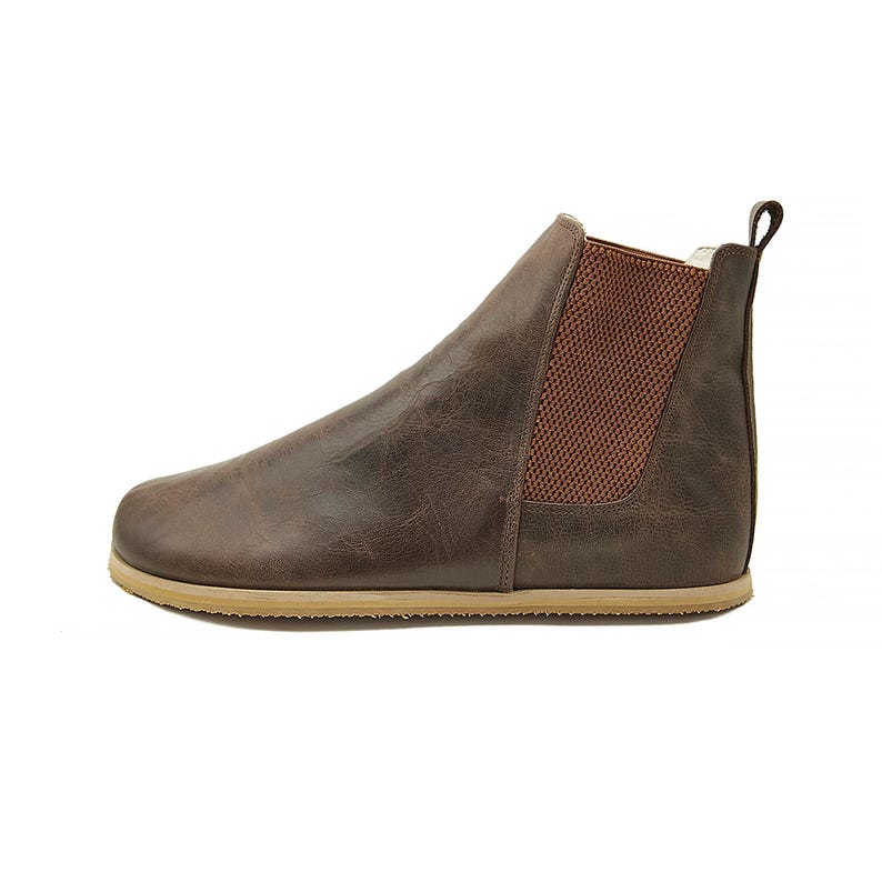 May include: Brown leather ankle boots with a brown elastic panel on the side and a light brown sole.