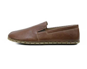 May include: A brown leather slip-on shoe with a rounded toe and a low profile. The shoe features a stitched sole and a simple, classic design. The shoe is made of a smooth, textured leather.