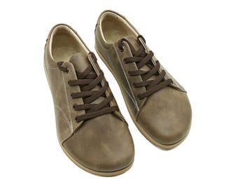 May include: A pair of brown leather lace-up shoes with white stitching. The shoes have a casual style and are made of a soft, comfortable material.