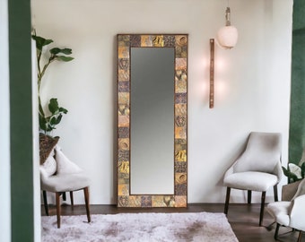 Puede incluir: Un espejo rectangular de cuerpo entero con un marco de mosaico decorativo. El marco presenta una mezcla de colores, incluyendo dorado, marrón y morado. El espejo está en una habitación con dos sillas, una alfombra y una planta.