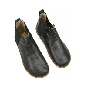 K&ouml;nnte beinhalten: Ein Paar schwarze Leder-Stiefeletten mit einem Schlupf-Design und einer abgerundeten Spitze.