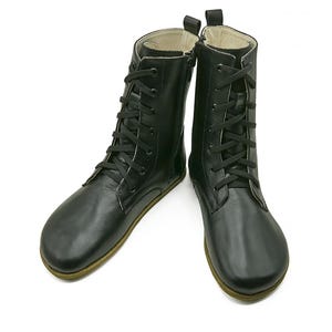 May include: A pair of black leather lace-up boots with a round toe and a zip on the side.