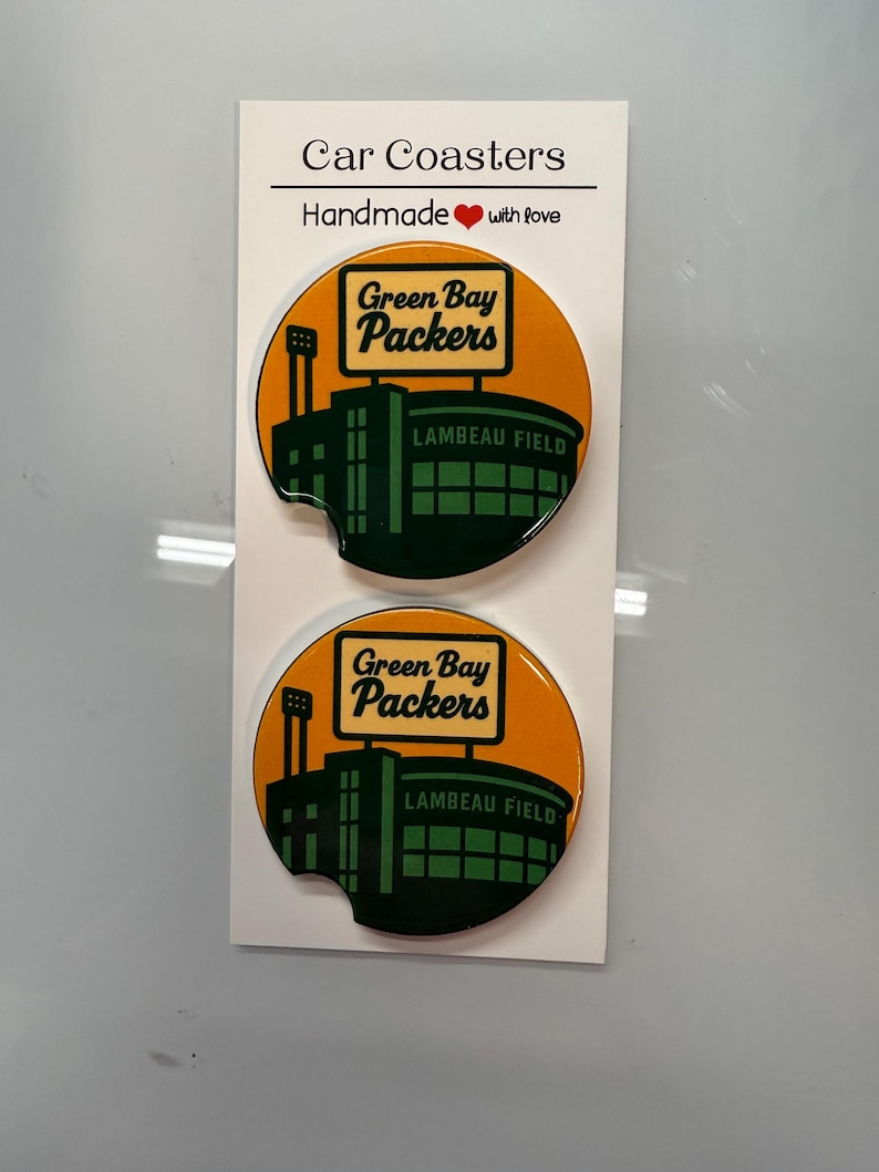 Puede incluir: Dos posavasos redondos para coche con el logotipo de los Green Bay Packers y el dise&ntilde;o del estadio Lambeau Field. Los posavasos son de color naranja y verde, con las palabras "Green Bay Packers" y "Lambeau Field". Hechos a mano.