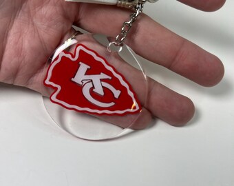 Llavero con la flecha de los KC Chiefs con borla blanca a juego