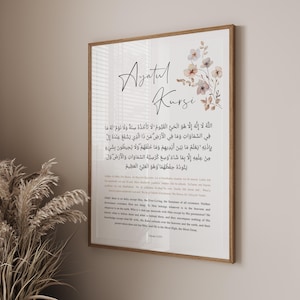 以下が含まれることがあります： 「Ayatul Kursi」の書道テキストを特徴とする額入りプリント。花柄のイラストが添えられています。木製のフレームに収められ、アラビア語のスクリプトと英語の翻訳が施されており、インテリア装飾に適しています。