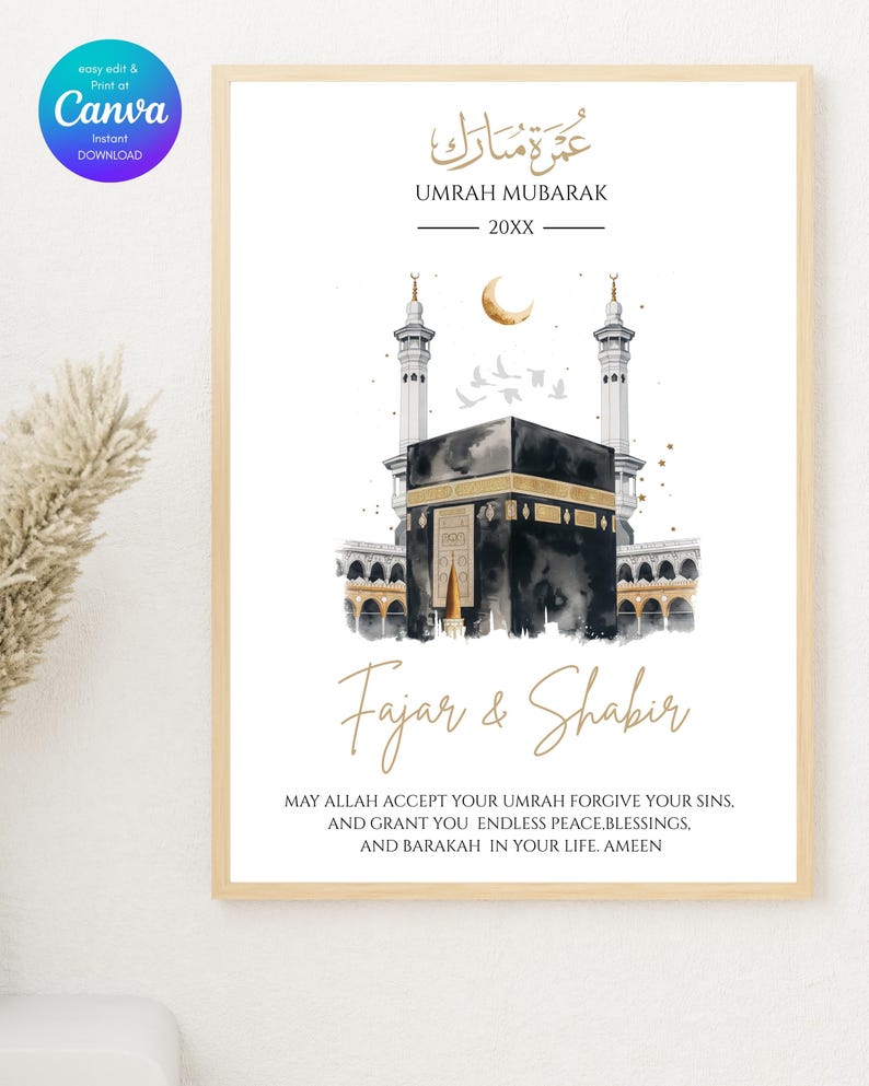 May include: A framed print with a watercolor illustration of the Kaaba in Mecca, with gold accents and Arabic calligraphy. The text reads "Umrah Mubarak" and "Fajar & Shabir," with a blessing below. The print is in a light wood frame.