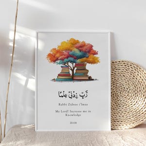 Puede incluir: Impresión artística enmarcada con un árbol colorido sobre pilas de libros. La impresión incluye caligrafía árabe y texto en inglés: "Rabbi Zidnee I'lmaa, ¡Señor mío! Aumenta mi conocimiento." La obra de arte se muestra sobre una superficie neutra.