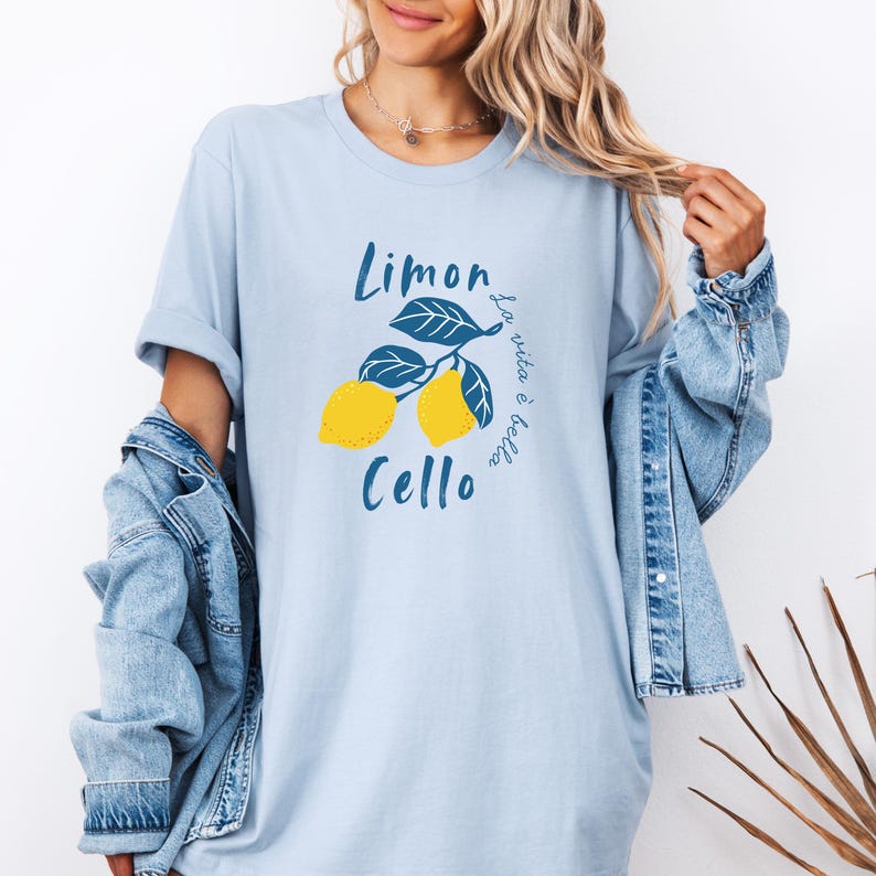 Light Blue Comfort Colors unisex shirt with yellow lemons and navy blue leaves, featuring “Limoncello” text and “La vita è bella” in script.