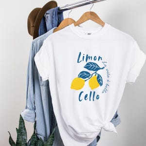 White Comfort Colors unisex shirt with yellow lemons and navy blue leaves, featuring “Limoncello” text and “La vita è bella” in script.