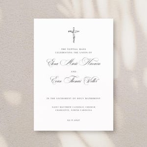 Puede incluir: Una tarjeta de invitación de boda blanca con una cruz y una escritura elegante. La tarjeta anuncia una misa nupcial que celebra la unión de Elena Marie Navarro y Evan Thomas Weller. La fecha 12.15.2027 está en la parte inferior, con los detalles de la iglesia.