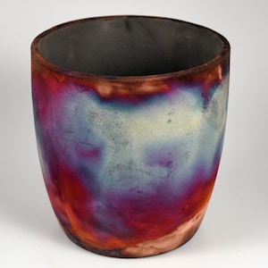 May include: A ceramic vase with a unique, colorful glaze. The glaze features shades of red, purple, blue, and yellow, creating a vibrant and abstract pattern.