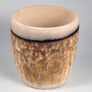 Puede incluir: Un pequeño macetero de cerámica marrón con un borde blanco y un esmalte craquelado.