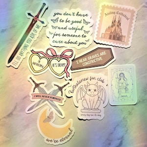 May include: A collection of assorted stickers featuring various designs including a sword with the text I'LL DO ANYTHING YOU ASK OF ME, a quote about being good and useful, a cathedral, heart-shaped charms, a gargoyle, and a tarot card.