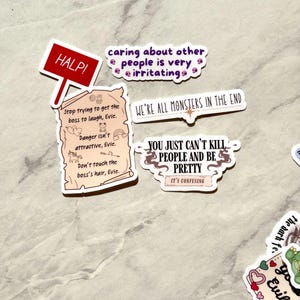 Puede incluir: Una colecci&oacute;n de pegatinas humor&iacute;sticas con varias frases y dise&ntilde;os. Una pegatina dice "HALP!" en un letrero rojo. Otras pegatinas incluyen frases como "caring about other people is very irritating" y "WE'RE ALL MONSTERS IN THE END."