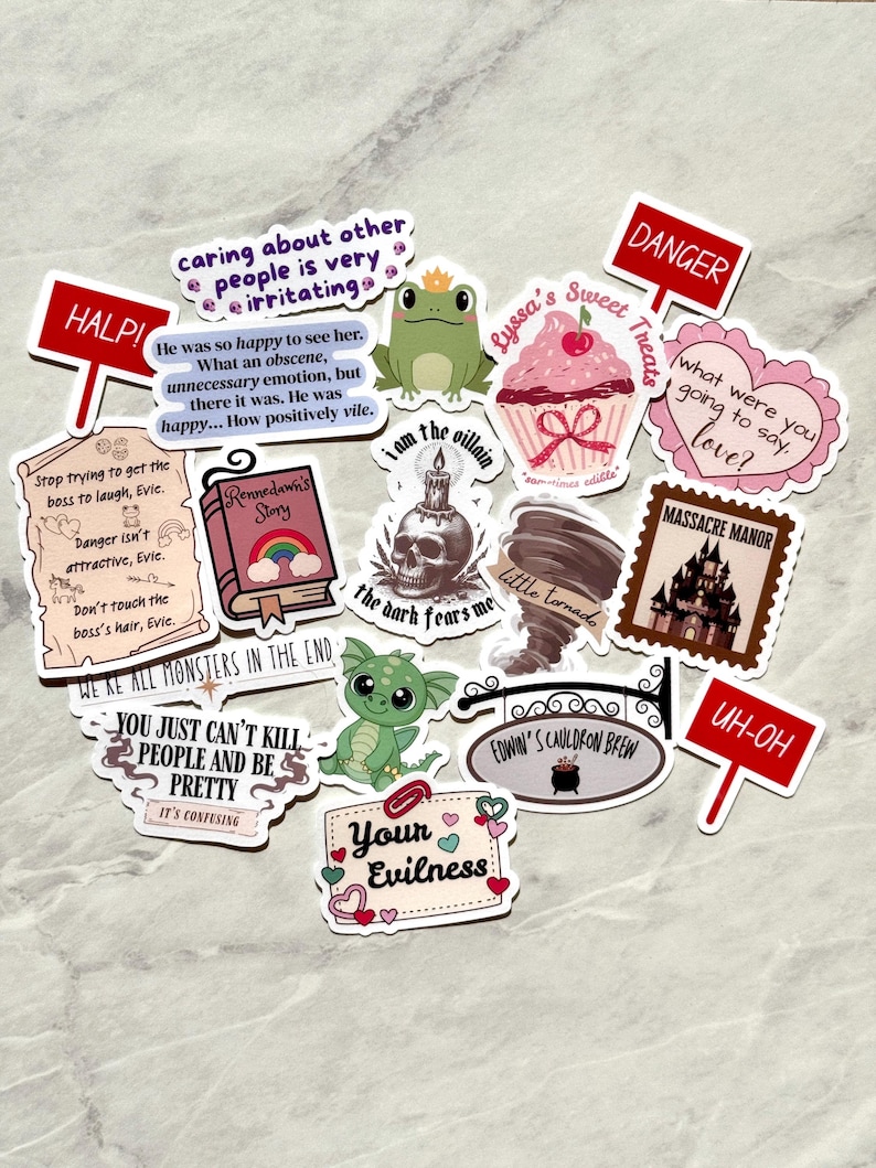 Puede incluir: Una colecci&oacute;n de pegatinas coloridas con varios dise&ntilde;os y texto. Los dise&ntilde;os incluyen una rana con corona, una magdalena, una calavera, un tornado, un castillo y frases como "HALP!" y "Your Evilness." Las pegatinas est&aacute;n dispuestas sobre una superficie gris claro.