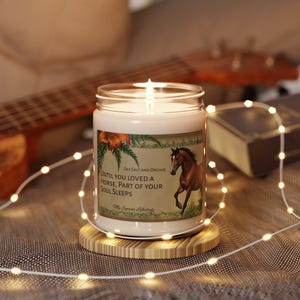 May include: A white candle with a brown horse illustration on the label. The label reads "Sea Salt and Orchid" and "Until you loved a horse, part of your soul sleeps". The candle is on a wooden coaster.