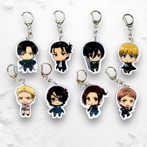 Könnte beinhalten: Satz mit zehn Anime-Charakter-Schlüsselanhängern mit Charakteren aus der beliebten Anime-Serie Attack on Titan. Die Schlüsselanhänger sind aus klarem Acryl gefertigt und zeigen farbenfrohe Illustrationen der Charaktere.
