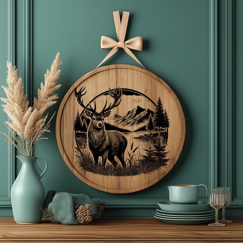 May include: A round wooden wall decor with a black and white illustration of a deer standing in a forest scene. The deer is in the center of the image and is surrounded by trees, a lake, and mountains. The background is a light brown color.