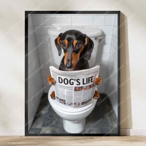 Pode incluir: Uma impressão artística emoldurada apresentando um dachshund preto e castanho sentado num vaso sanitário branco num banheiro azulejado. O cão segura um jornal com a manchete DOG'S LIFE impressa em letras pretas em negrito. A moldura é fina e preta.