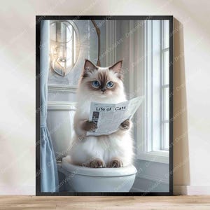 Könnte beinhalten: Ein gerahmter Wandkunstdruck, der eine flauschige weiß-braune Katze mit leuchtend blauen Augen zeigt, die auf einer weißen Toilette sitzt. Die Katze hält eine Zeitung mit der Schlagzeile Life of Cats und liest darin. Die Szene spielt in einem Bad.