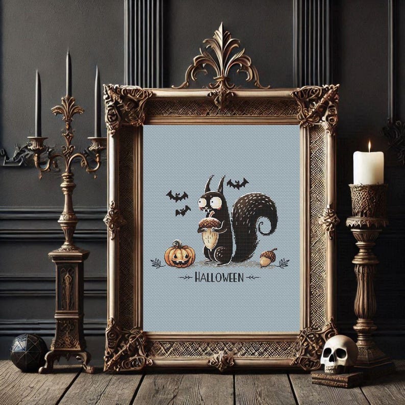 May include: A framed cross-stitch featuring a black squirrel holding an acorn, a jack-o'-lantern, and bats. The word "HALLOWEEN" is stitched below. The frame is ornate, gold-colored, and sits on a wooden surface.